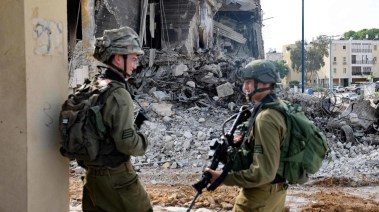 جنديان من جيش الاحتلال مبتسمان وسط دمار كبير لحق بأحد المناطق في قطاع غزة