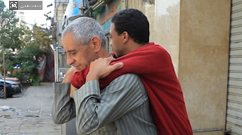 أب يحمل ابنه المصاب بشلل كلي على ظهره