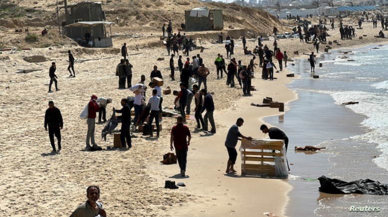 فلسطينيون يلتقطون المساعدات أمام بحر غزة