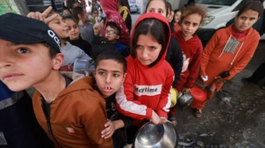 اطفال من غزة ينتظرون استلام وجبات الطعام نصيبهم الضئيل من المساعدات