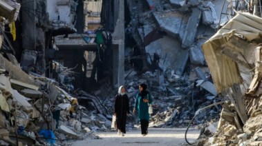 فلسطينيتان تسيران وسط الانقاض في غزة