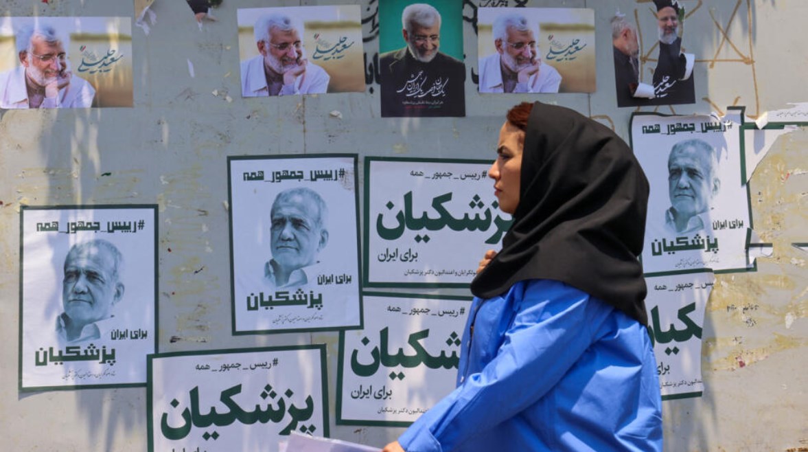 مواطنة إيرانية وبجانبها لافتات دعائية للمرشحين