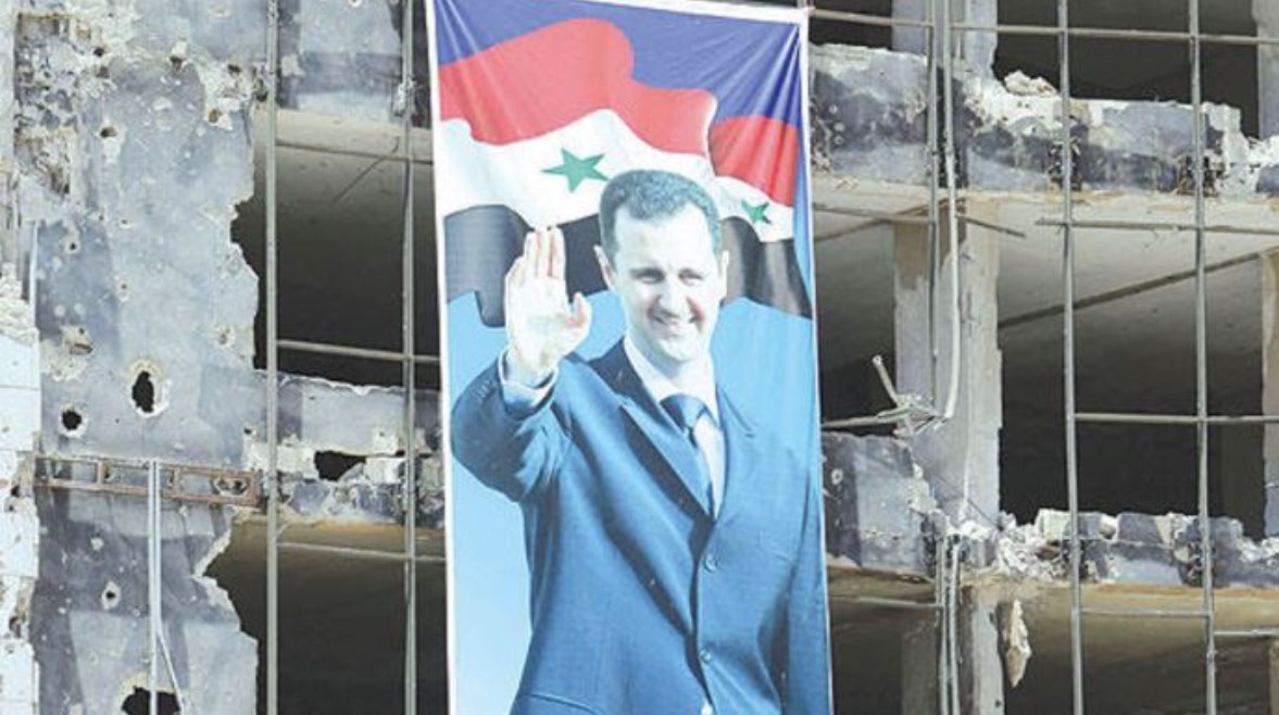صورة لبشار الأسد معلقة على واجهة مبنى مدمر في سوريا
