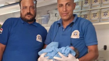 مسعفان ويحمل أحدهما المولودة