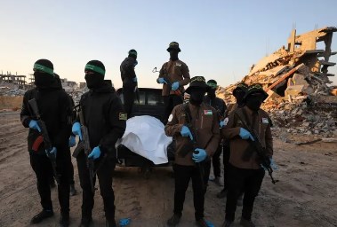 عناصر من حماس برفقة جثة عثروا عليها قبل تسليمها لإسرائيل
