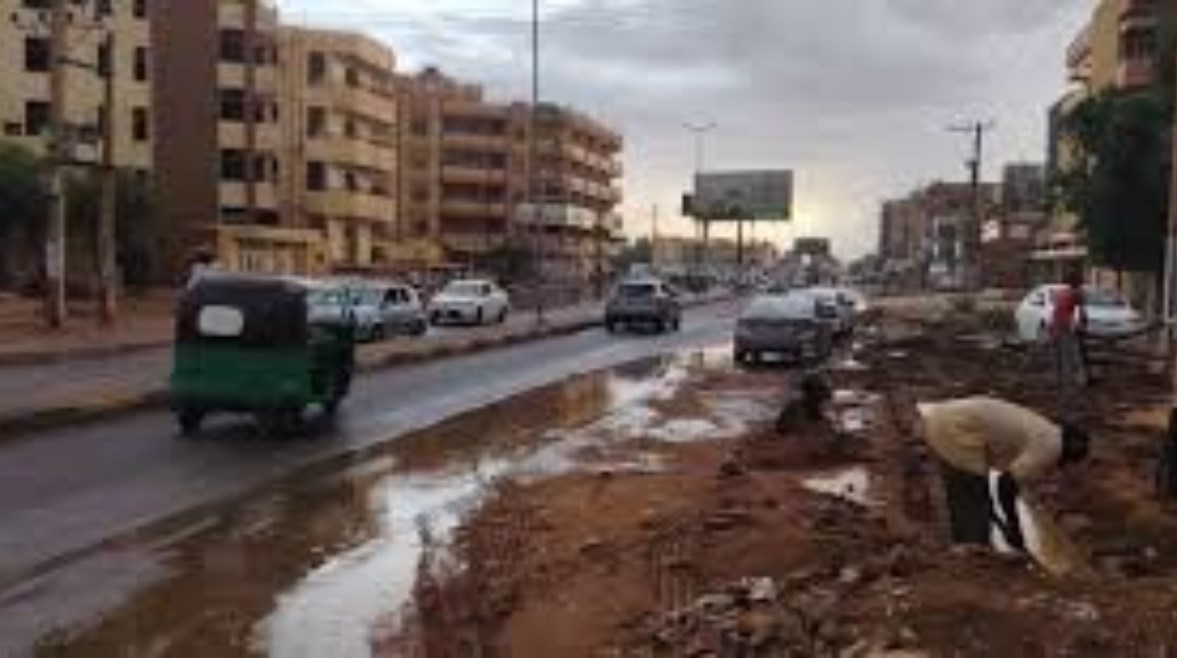 مواطن يحاول تصريف المياه من أمام مسكنه في مدينة أم درمان ( مصدر الصورة: الشرق الأوسط)