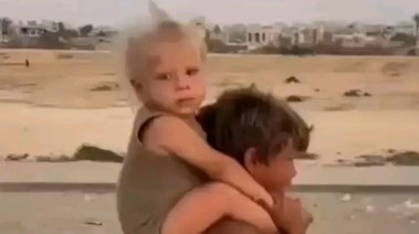 طفل فلسطيني يحمل شقيقته الصغيرة 
