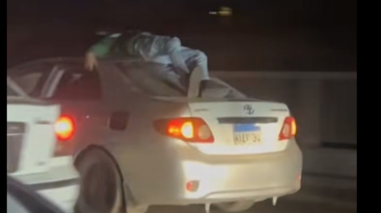 شخص مستلقى أعلى سقف سيارة بصفط اللبن