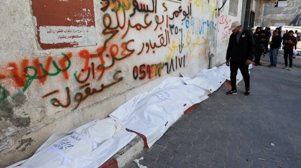 شاب يقف بجوار جثامين فلسطينيين قضوا في غارة إسرائيلية