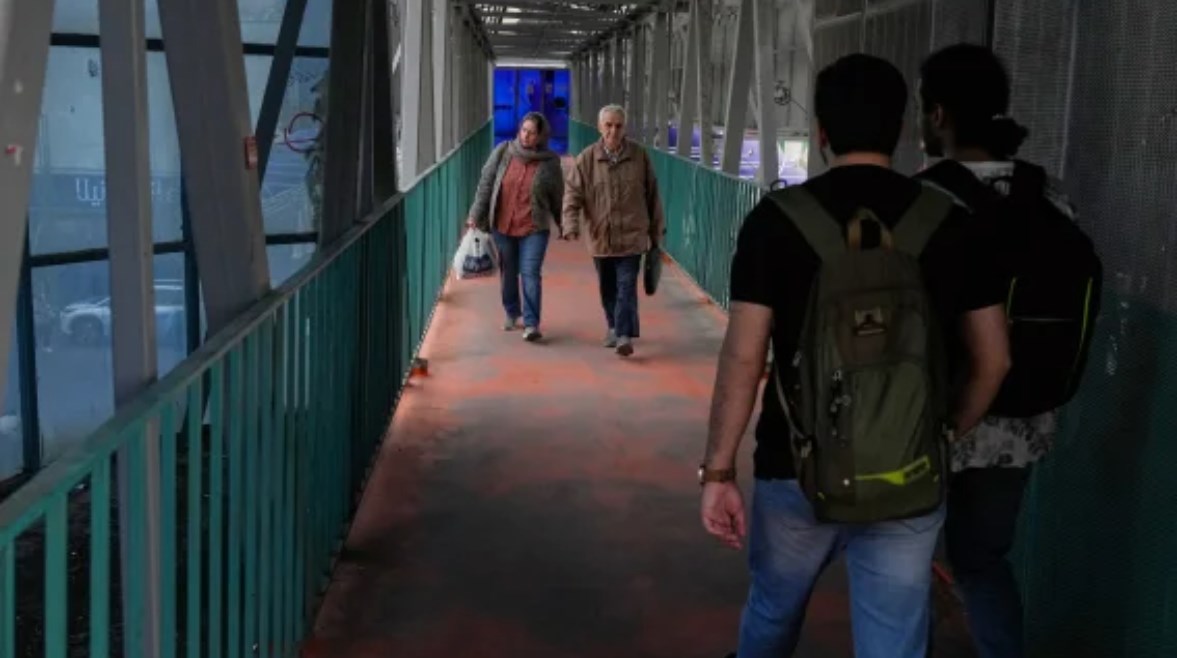 إيرانيون يسيرون فوق كوبري علوي للمشاة في طهران