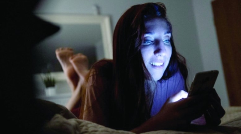 الضوء الأزرق المنبعث من شاشات الهواتف أمام الفتاة 