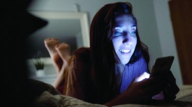 الضوء الأزرق المنبعث من شاشات الهواتف أمام الفتاة 