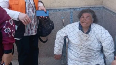 صور لسيدة مُسنة تجلس على كرسي متحرك في حالة صحية سيئة