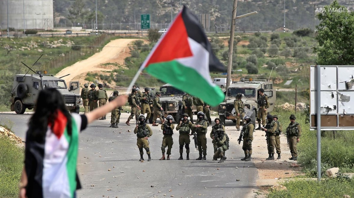 فناة ترفع العلم الفلسطيني في وجه جنود الإحتلال